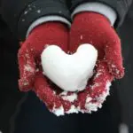 person holding heart-shaped snow