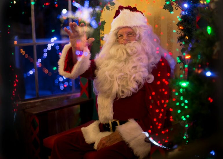 santa claus sitting beside lit tree